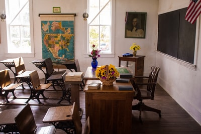空荡荡的白色教室，墙上有椅子、桌子和地图